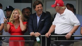 U.S. Rep. Marjorie Taylor Greene, left, Tucker Carlson, center, and former President Donald Trump, right, react during the final round of the Bedminster Invitational LIV Golf tournament in Bedminster, N.J., Sunday, July 31, 2022. Fox News said Monday it has “agreed to part ways” with Carlson, its popular and controversial host, less than a week after settling a lawsuit over the network’s 2020 election reporting.