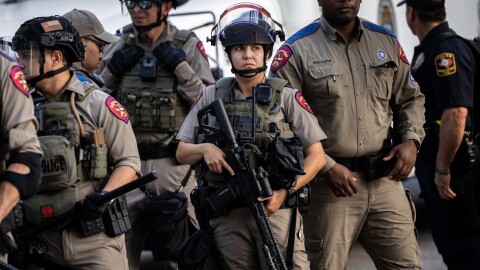 Texas State Troopers stand in a group holding weapons. 