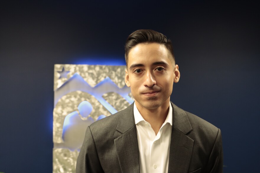  a man stands against a dark blue background
