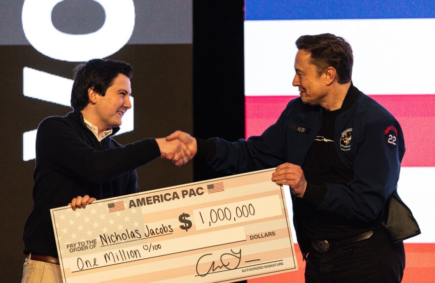 FILE - Elon Musk hands over a million dollar check to Nicholas Jacobs during a town hall in Green Bay, Wis., March 30, 2025.
