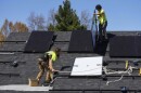 Two men install solar panels on the roof of a home.