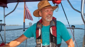 Bill Streever smiles and looks into the distance while sailing a boat.