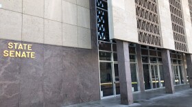 Gold letters read "State Senate" on dark stone building