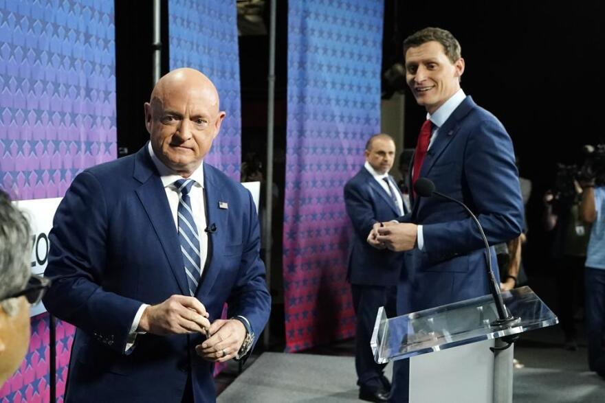 Arizona Democratic Sen. Mark Kelly, left, Republican challenger Blake Masters, right, and Libertarian Marc Victor, back, pause on the stage prior to a televised debate in Phoenix, Thursday, Oct. 6, 2022.