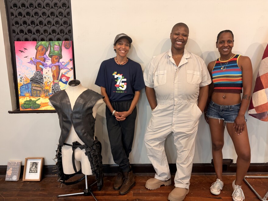 From left to right, mars patterson, Destiny Brady, and Fatima Laster pose around artwork that is part of the "This Is America Exibition.