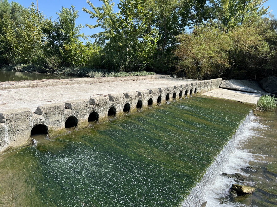 Water flows through a low-head dam.