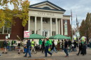 A group of people holding picket signs on a sidewalk in front of the Corvallis City Hall.