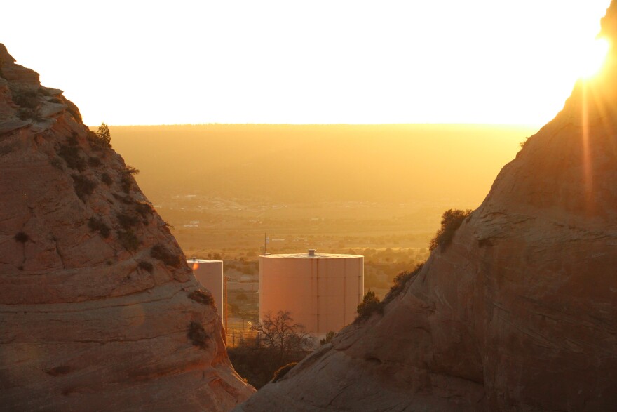 An orange sunset with a large water tank framed by desert red rock