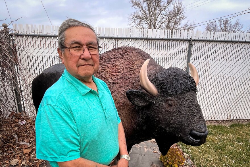 Virgil Johnson of the Confederated Tribes of the Goshute Reservation stands next to a bison statue outside his home in Sandy, Utah, March 27, 2025. Native elders like Johnson are lending their perspectives to Project Archaeology’s work as the program looks to tell a fuller picture of history.