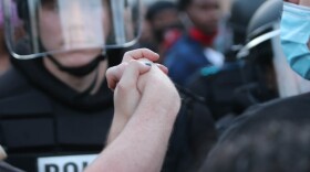 Protesters join hands as they face police officers in San Antonio on May 30, 2020.