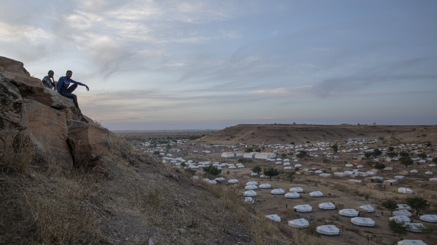 Tigrayan men sit atop a hill in Ethiopia overlooking part of the Umm Rakouba refugee camp in neighboring Sudan, where many people who fled the ongoing conflict have gone for refuge.