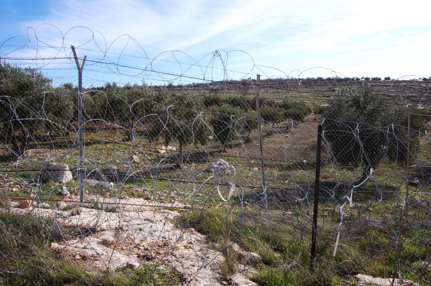 This fence enclosing part of the Israeli settlement of Tekoa was breached by a Palestinian attacker last month. Some Israel settlers want better fences. Other don't want to live inside barbed wire.