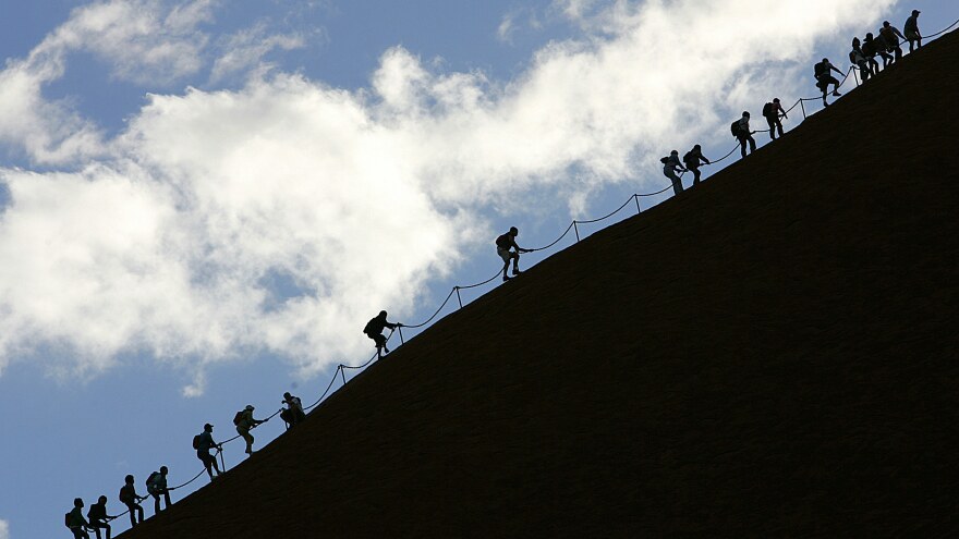 Tourists climb the monolith of Uluru — against the wishes of the Anangu, the traditional owners of the rock — in the Uluru-Kata Tjuta National Park in Central Australia in November 2005. Uluru will be closed to climbers beginning in October 2019.