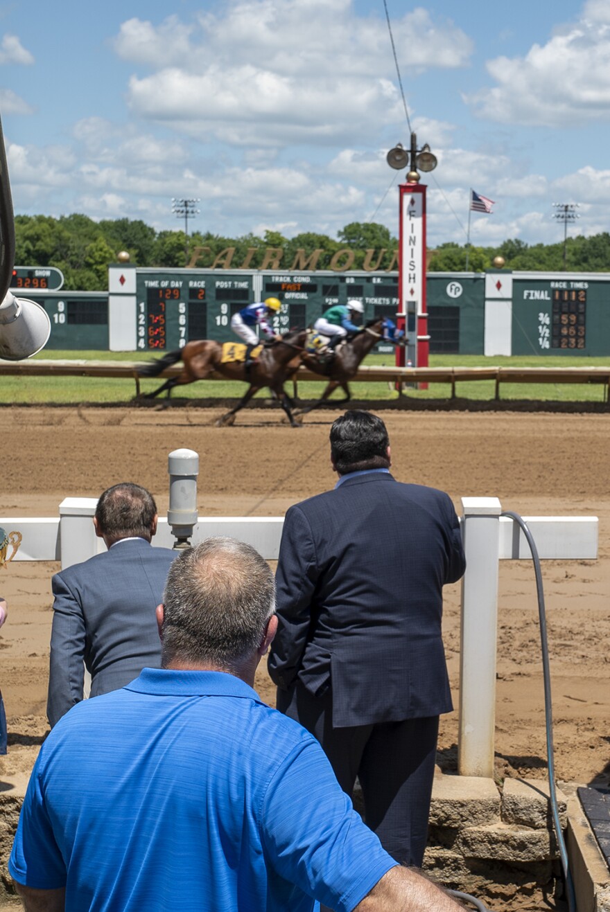 Gov. J.B. Pritzker watches horses cross the finish line at Fairmount Racetrack on July 30. 