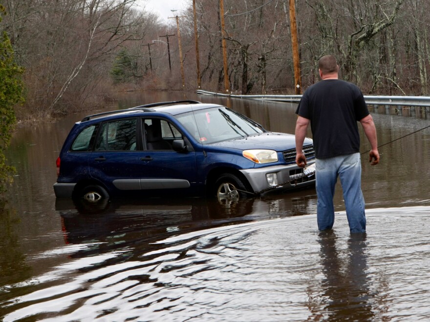 A tow truck operator checks on a car he is pulling out of a flooded road in Exeter, R.I., on Wednesday, March 31, 2010.