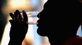 A man takes a drink of water. (Darren England/Getty Images).