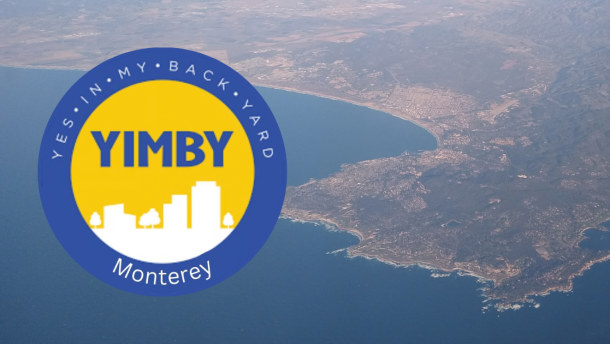 A logo with a blue ring and white text, and a yellow center with white buildings in silhouette and blue letters. Behind it is an aerial view of water with a landmass.