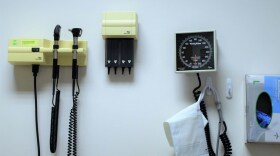 A blood pressure cuff and other medical equipment hang on the wall of an exam room.