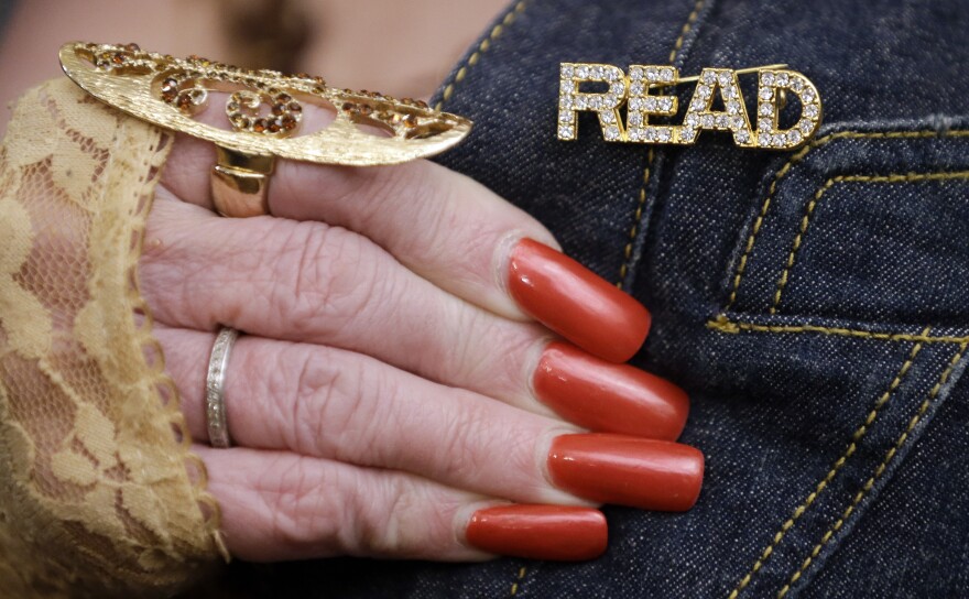 Dolly Parton displays a pin that she wears on her jacket during a celebration of the tenth anniversary of the Governor's Books from Birth Foundation on Tuesday, Sept. 30, 2014, in Nashville, Tenn. The foundation distributes books to all children in Tennessee free of charge through age five.(AP Photo/Mark Humphrey)