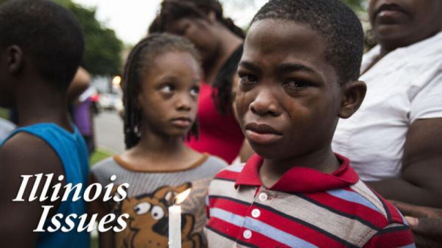A boy holds a candle at a memorial for his 19-year-old cousin who was shot to death in Chicago.