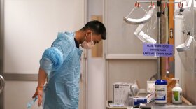 Respiratory therapist Bailey Synhavong begins to put on protective equipment, which will include a face shield, gloves, gown, head cover and mask, before going into a patient's room in the COVID intensive care unit at UW Medical Center on Tuesday.