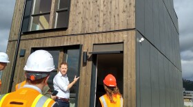 A man gestures at a structure made from cross-laminated timber.