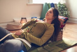 Serene lady relaxing and meditating on a yoga mat in a cosy house