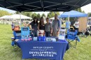 four people stand around an event table smiling at the camera