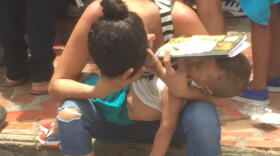 WORST HUMANITARIAN CRISIS: An exhausted Venezuelan refugee tries to give her toddler son shade while waiting for food stamps in Cucuta, Colombia, this year.
