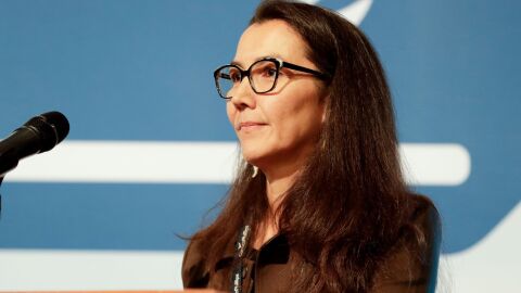 A woman behind a microphone, with a blue background