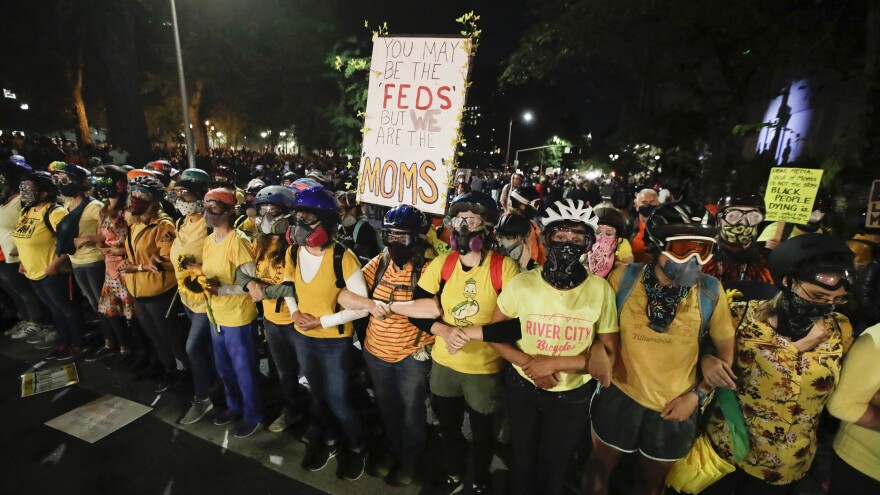 Members of the 'Wall of Moms" lock their arms during a Black Lives Matter protest at the Mark O. Hatfield United States Courthouse on Thursday in Portland, Ore.