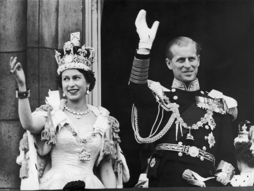 Queen Elizabeth II and the Duke of Edinburgh wave at the crowds from the balcony at Buckingham Palace on June 2, 1953.