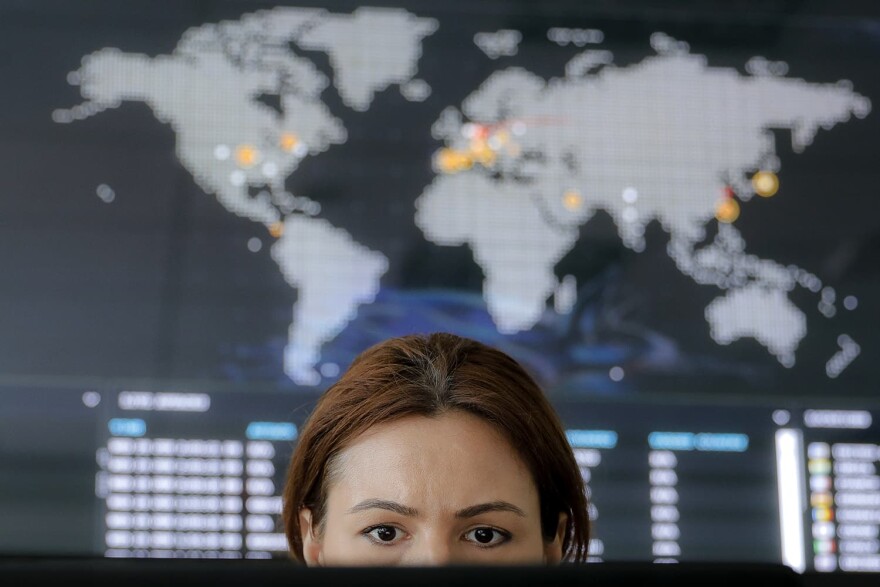 A woman looks at a computer monitor back dropped by a real time cyber-attacks world map, at the headquarters of Bitdefender in Bucharest, Romania, Wednesday, June 28, 2017. (Vadim Ghirda/AP)