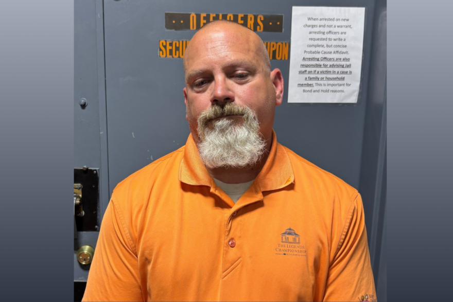 The mugshot of Officer Thomas Burkhardt in an orange collared shirt. 
