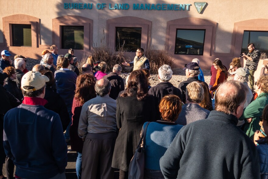 A Bureau of Land Management official addresses a crowd in front of his office building.