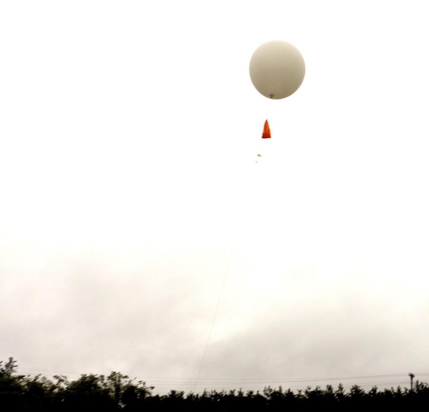 A weather balloon moments after release at the National Weather Service office in Gaylord. The radiosonde is just below the orange flag.