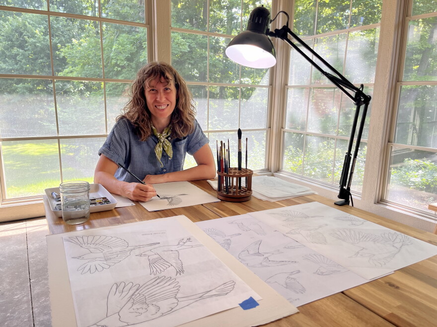 Rebecca Jabs (pictured above) is an ARTservancy resident at Forest Beach Migratory Preserve. She is pictured sitting at a table working on artwork. 