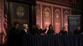 FILE - The archbishop of Miami, Thomas Wenski, raises his hand while addressing a crowd during a panel on immigration at Georgetown University in Washington, Thursday, Sept. 11, 2025.