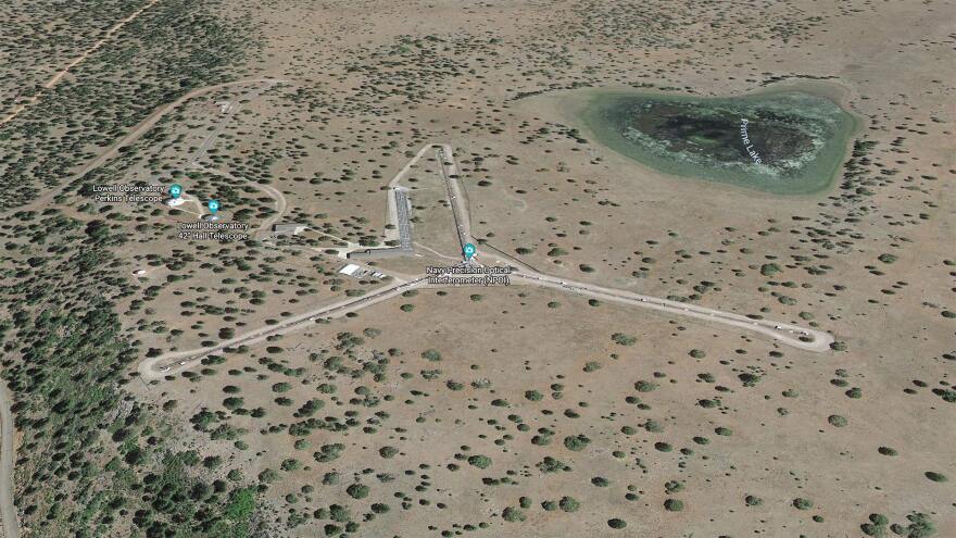 An aerial view of a desert landscape with sparse trees and a Y-shaped construct in teh center. 