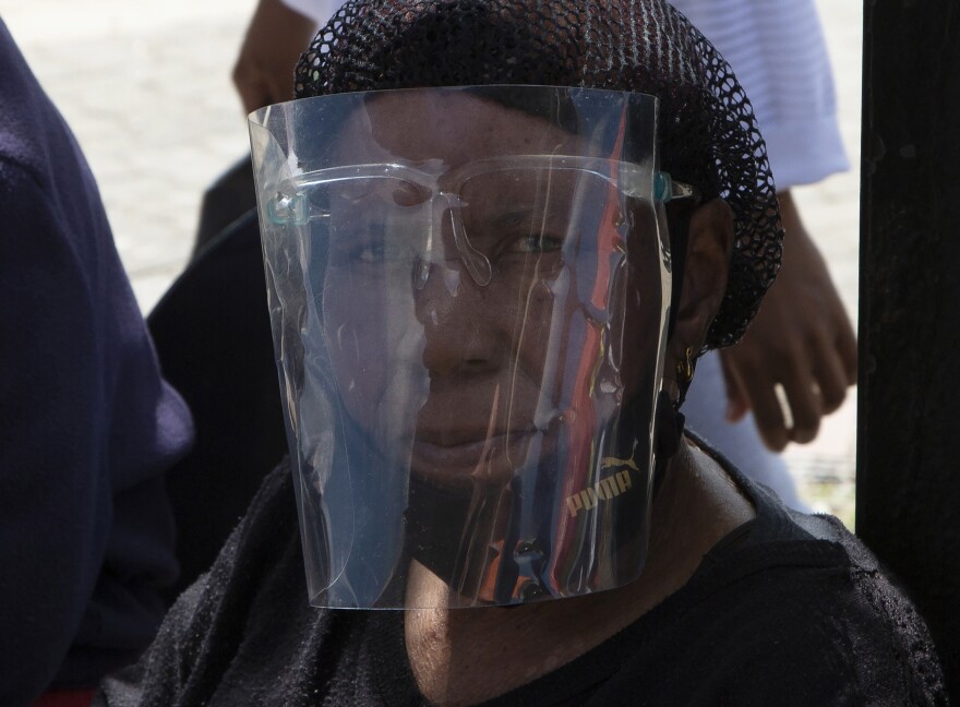 A woman wears a face shield to protect against COVID-19 at a taxi rank in Soweto, South Africa, Tuesday, April 5, 2022. South Africa is seeing a rapid surge of COVID-19 cases from a sub-variant of omicron, say health experts.