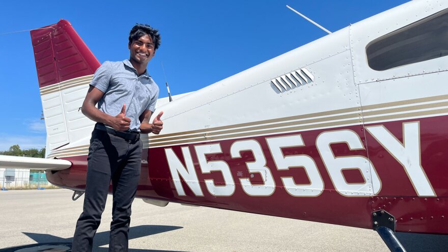 19-year-old Nathan Baskar will graduate from SIU this month.  He poses proudly next to the tail of an airplane.