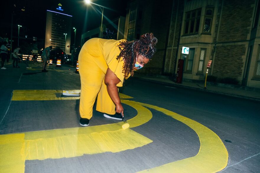 San Antonio poet laureate Andrea "Vocab" Sanderson paints the words of her poem on downtown streets.