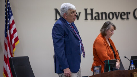 Board members David Perry, left, and Judy Justice, right, listen to God Bless America before the start of the New Hanover County Schools Board of Education meeting in Wilmington on July 8, 2025. Many teachers and community members attended to show their support for the Mary W. Howe Pre-K Center which was under consideration for closure.
