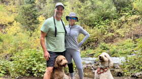 A photo of Joe and Debbi Bellinghieri hiking in Park City with their two dogs Charlee (left) and Murphee (right).