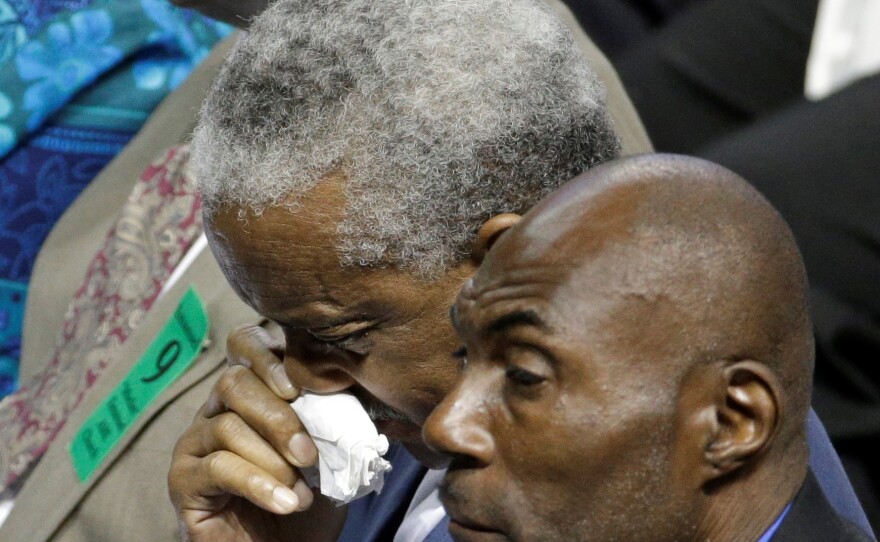 Rev. Anthony Thompson, background, husband of victim Myra Thompson, wipes his face during a memorial in Charleston, S.C., Friday, June 17, 2016 on the anniversary of the killing of nine black parishioners during bible study at Mother Emanuel AME Church.
