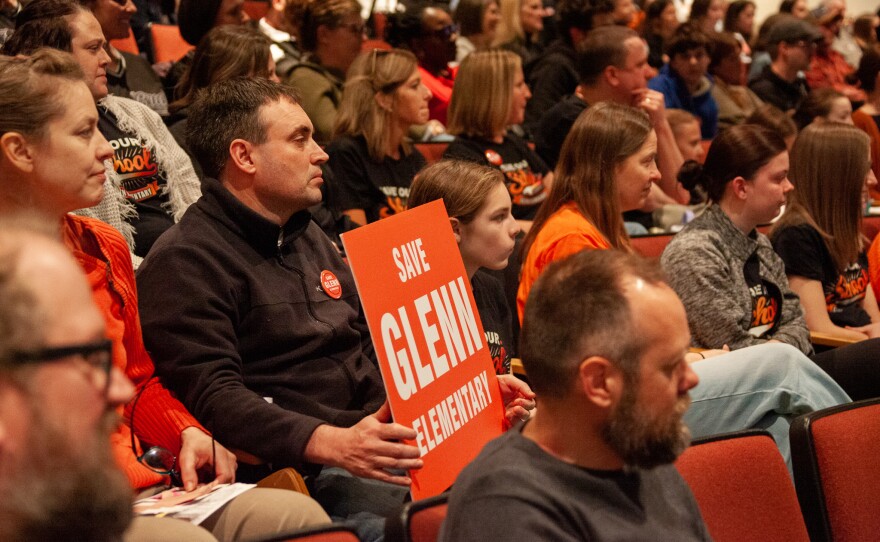 Parent Kevin Bersett holds a sign during Wednesday's school board meeting
