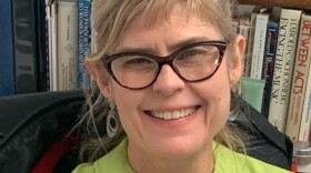 A headshot of Kati Harrison wearing cat-eye glasses and a green blouse