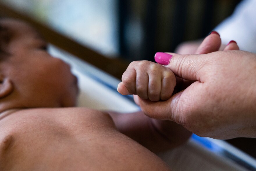 Registered Nurse Carole Kriessman performs a quick check up on Ja'Mil'Lion DeLorenzo's 4-week-old son, Haiyden, at DeLorenzo's grandmother's home in Glenolden, Pa., on June 9.