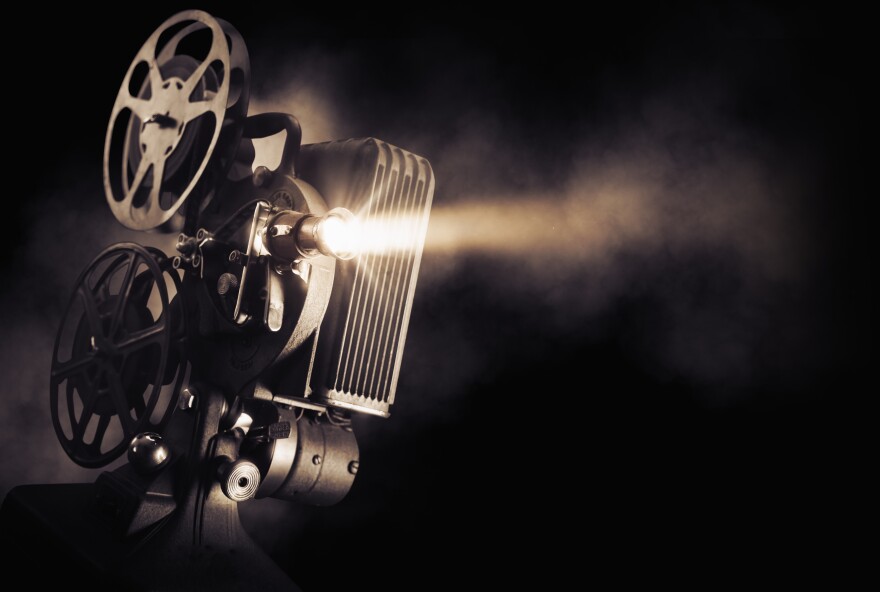 Movie projector on a dark background with light beam.