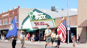 Local Boy Scouts carry flags down Illinois Street in a parade marking the 150th anniversary of the founding of the city of Sidney, Nebraska.